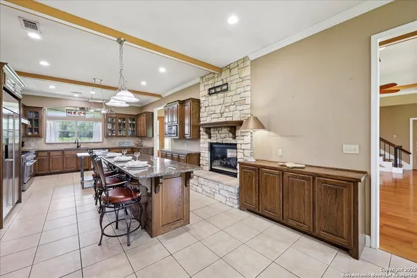a open kitchen with stainless steel appliances kitchen island granite countertop a table chairs and a refrigerator