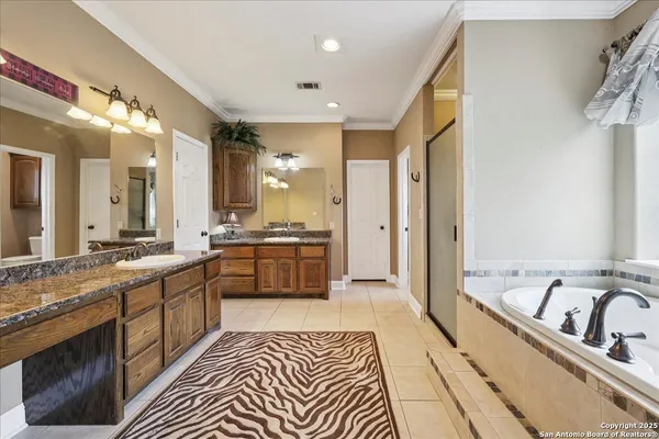 a large bathroom with a double vanity sink a mirror a bathtub and shower