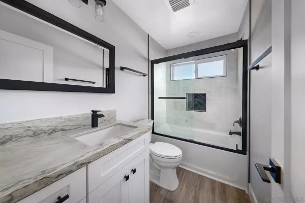 a bathroom with a granite countertop sink mirror vanity and toilet