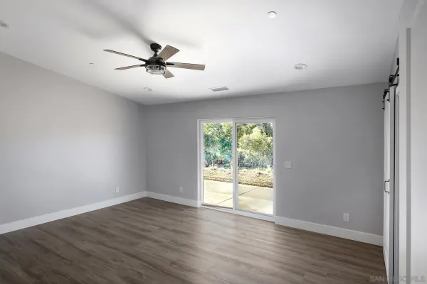 an empty room with wooden floor fan and windows