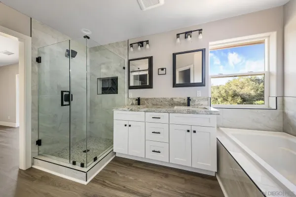 a bathroom with a granite countertop tub sink shower and mirror