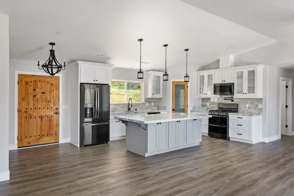 a kitchen with stainless steel appliances kitchen island granite countertop a refrigerator stove and oven with wooden floor