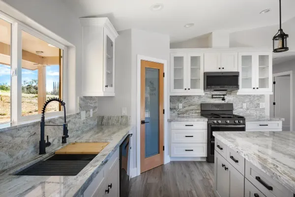 a kitchen with granite countertop a sink stove and refrigerator