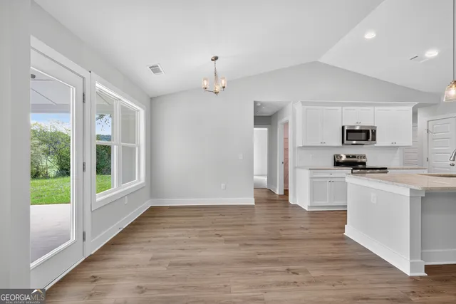 an empty room with wooden floor a ceiling fan and windows
