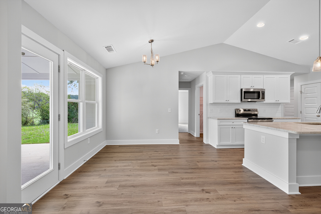 435 Watson Road Winder, GA 30680 - Photo 14 of 36 a kitchen with stainless steel appliances granite countertop a refrigerator a sink dishwasher a oven with white cabinets and wooden floor