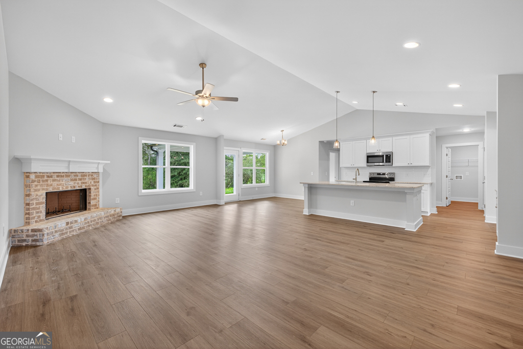 435 Watson Road Winder, GA 30680 - Photo 6 of 36 a view of an empty room and a kitchen with wooden floor and a kitchen