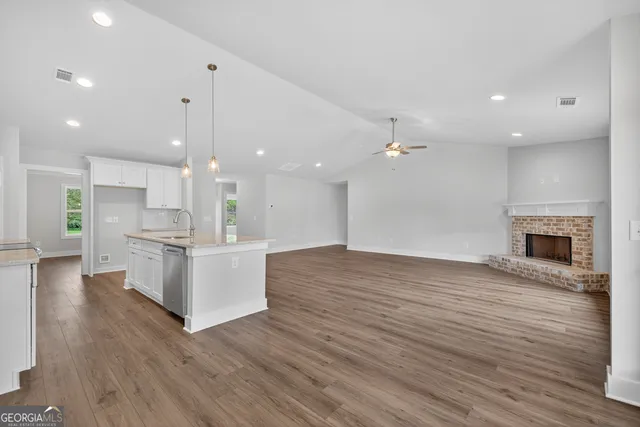 a view of an empty room with wooden floor and a fireplace
