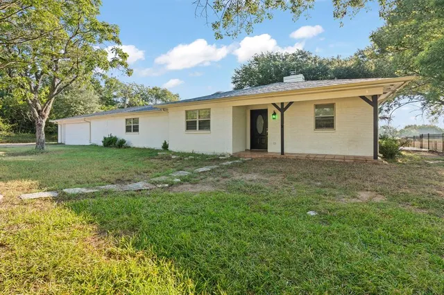 a view of house with yard and trees in the background