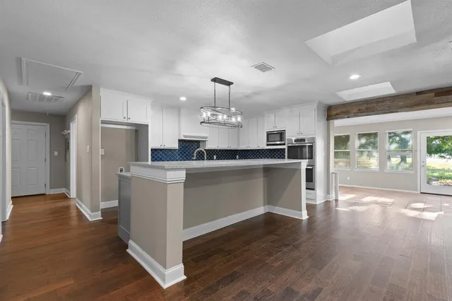 a kitchen with kitchen island a sink stainless steel appliances and wooden floor