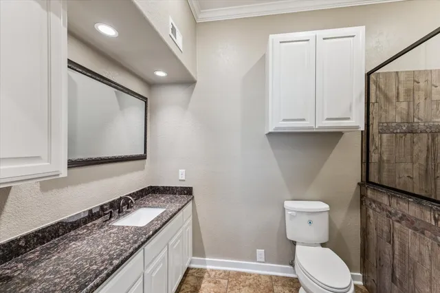 a bathroom with a granite countertop toilet sink and mirror