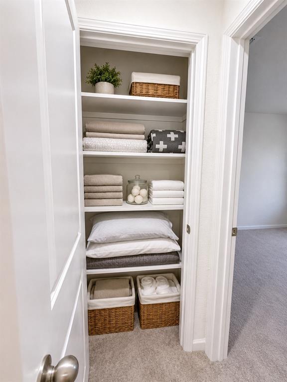 824 Juniper Street Anna, TX 75409 - Photo 14 of 25 Integrated linen closet featuring five fixed shelves, white painted trim, and neutral-toned carpeting