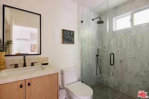 a bathroom with a granite countertop sink toilet and shower