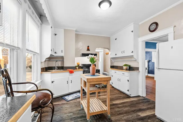 a kitchen with a refrigerator a stove a sink dishwasher and white cabinets with wooden floor