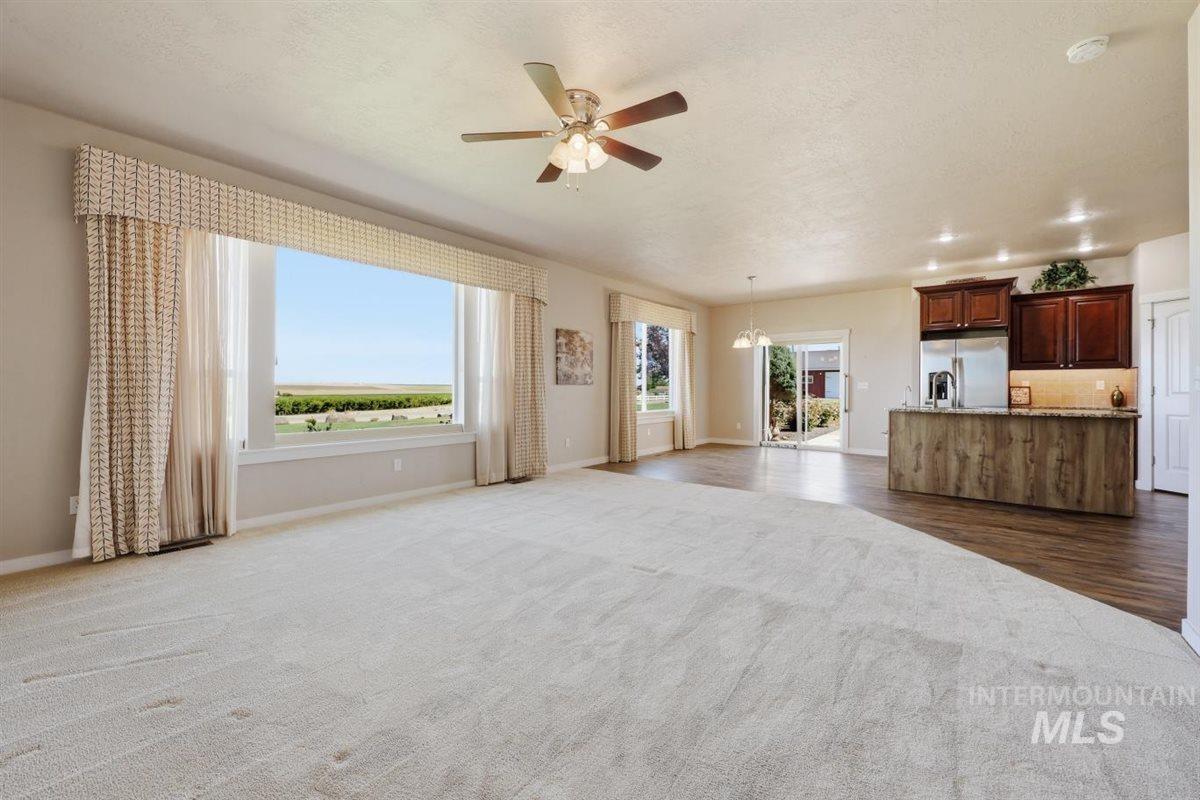 13496 Hockberger Ranch Road Caldwell, ID 83607 - Photo 20 of 40 Expansive open-concept living area featuring a large picture window, light-colored carpeting, a ceiling fan, and recessed lighting