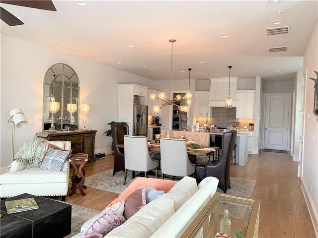 a living room with furniture kitchen view and a chandelier