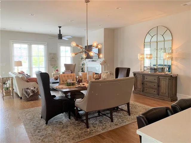 a living room with couches a fireplace and a dining table with wooden floor