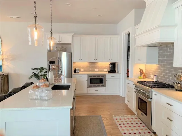 a kitchen with stainless steel appliances kitchen island granite countertop a sink a stove and a refrigerator