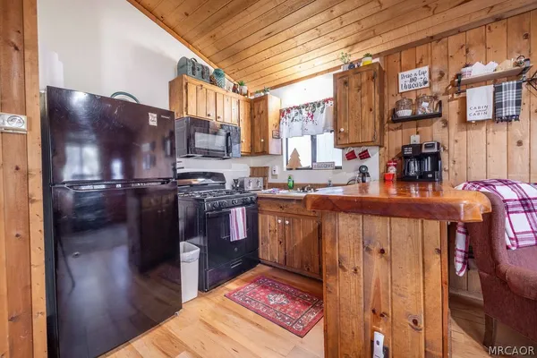a kitchen with stainless steel appliances granite countertop a refrigerator a stove and a sink with wooden cabinets