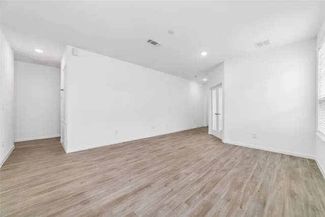 a view of an empty room with wooden floor and closet
