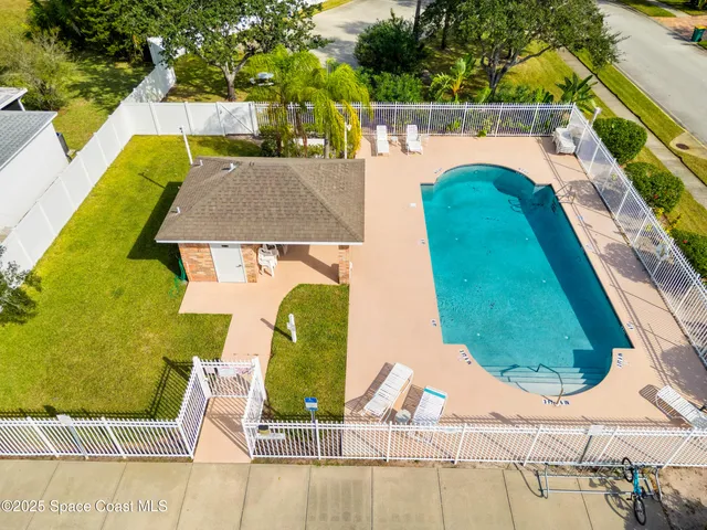 an aerial view of a house with swimming pool and large trees