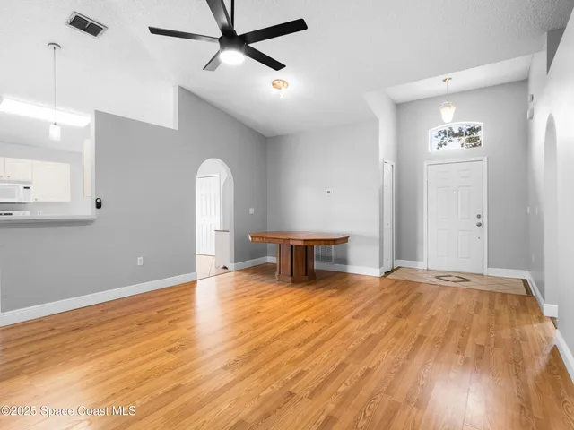 a view of an empty room with window and wooden floor