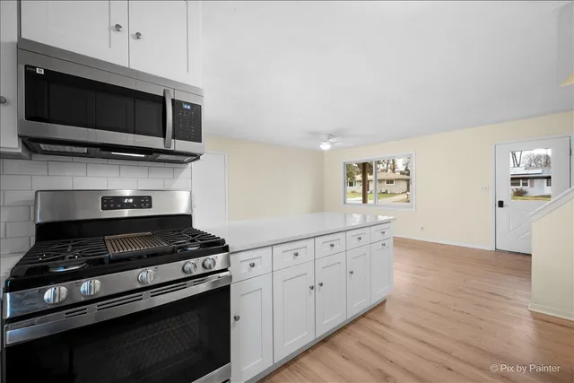 a kitchen with stainless steel appliances a white cabinet and a stove top oven