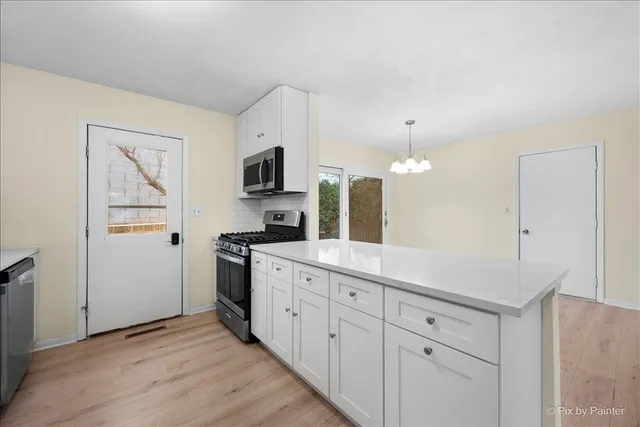 a kitchen with cabinets stainless steel appliances a sink and wooden floor