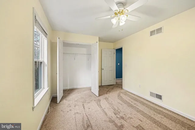 an empty room with windows and fan