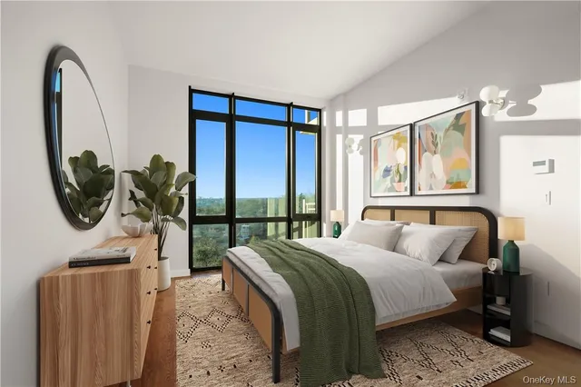 a bedroom with a bed a mirror on the dresser and a large window