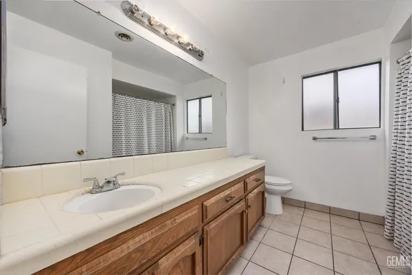 a bathroom with a granite countertop sink a toilet and mirror