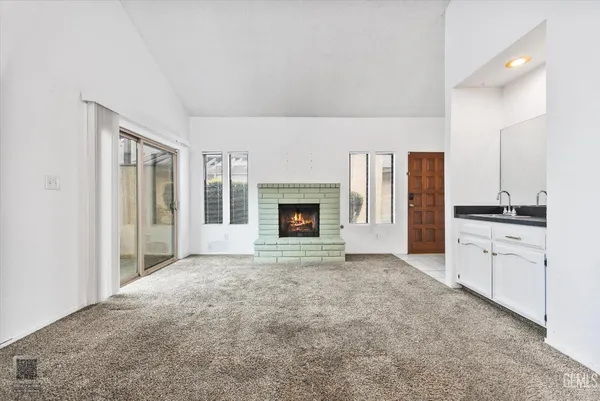 a living room with furniture a fireplace and a open kitchen view