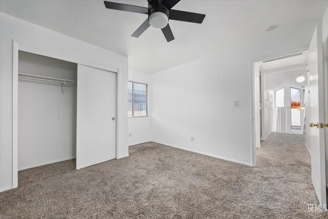a view of an empty room and chandelier fan