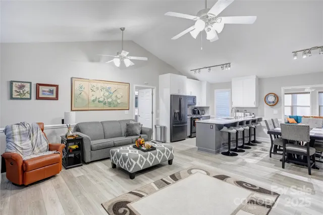 a living room with furniture kitchen view and a chandelier