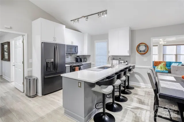 a kitchen with stainless steel appliances a table chairs and refrigerator