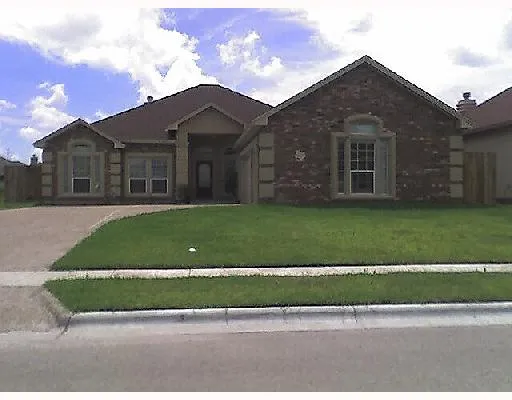 a view of a brick house next to a yard with big trees