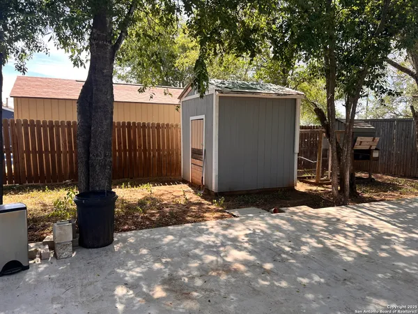 a view of backyard with wooden fence and large trees
