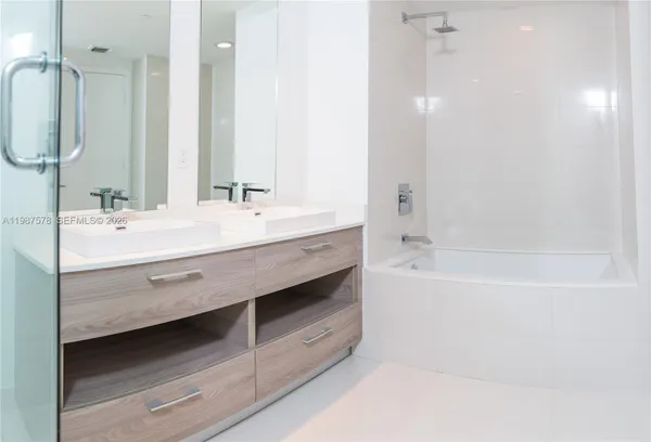 a bathroom with a double vanity sink a mirror and a bathtub