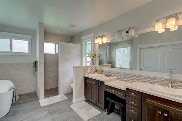 a bathroom with a granite countertop sink a toilet a mirror and shower