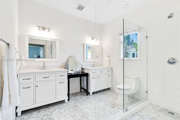 a spacious bathroom with a double vanity sink a mirror a window and a bathtub