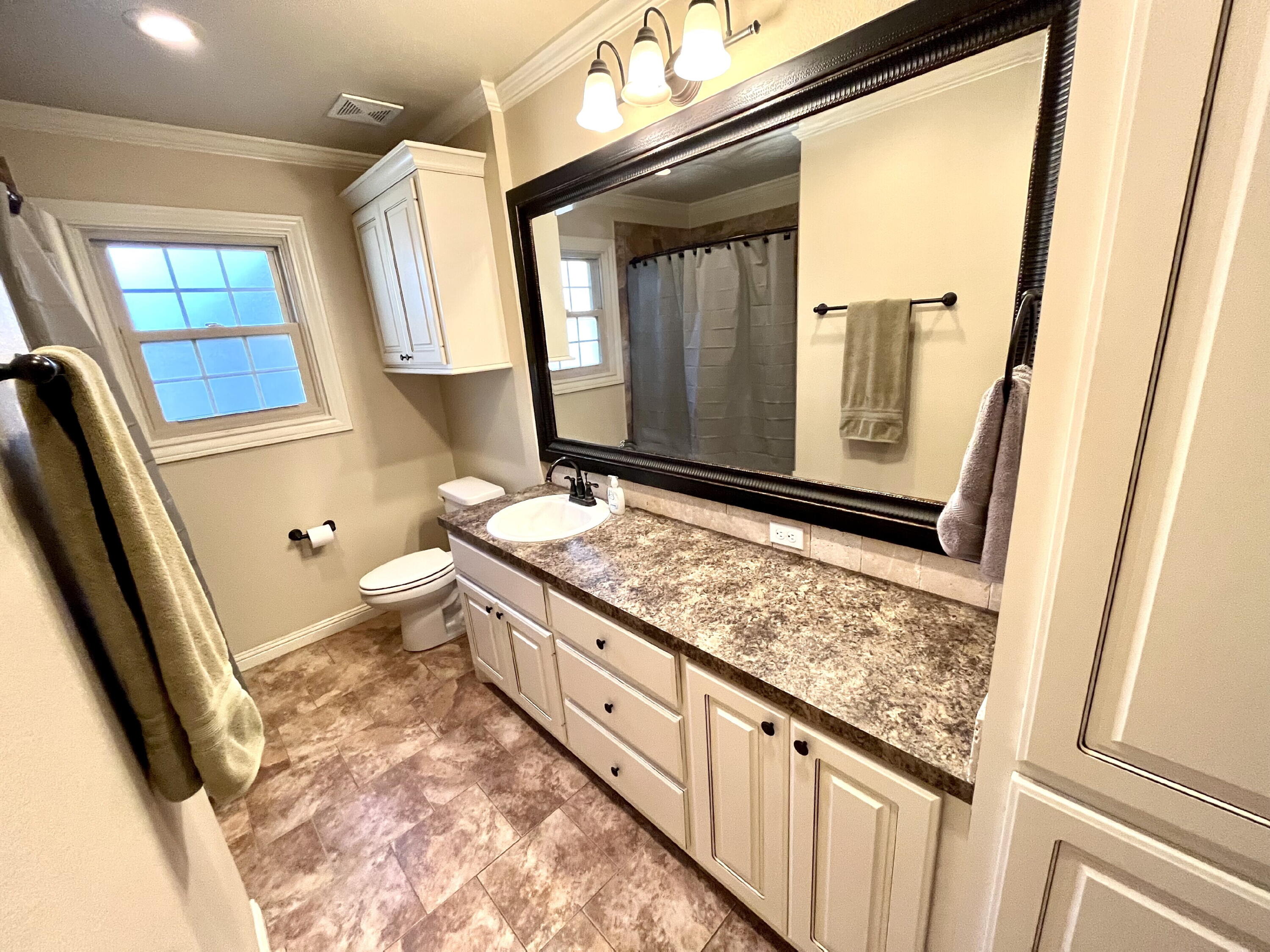 3321 55th Street Lubbock, TX 79413 - Photo 15 of 26 a bathroom with a granite countertop sink and a mirror
