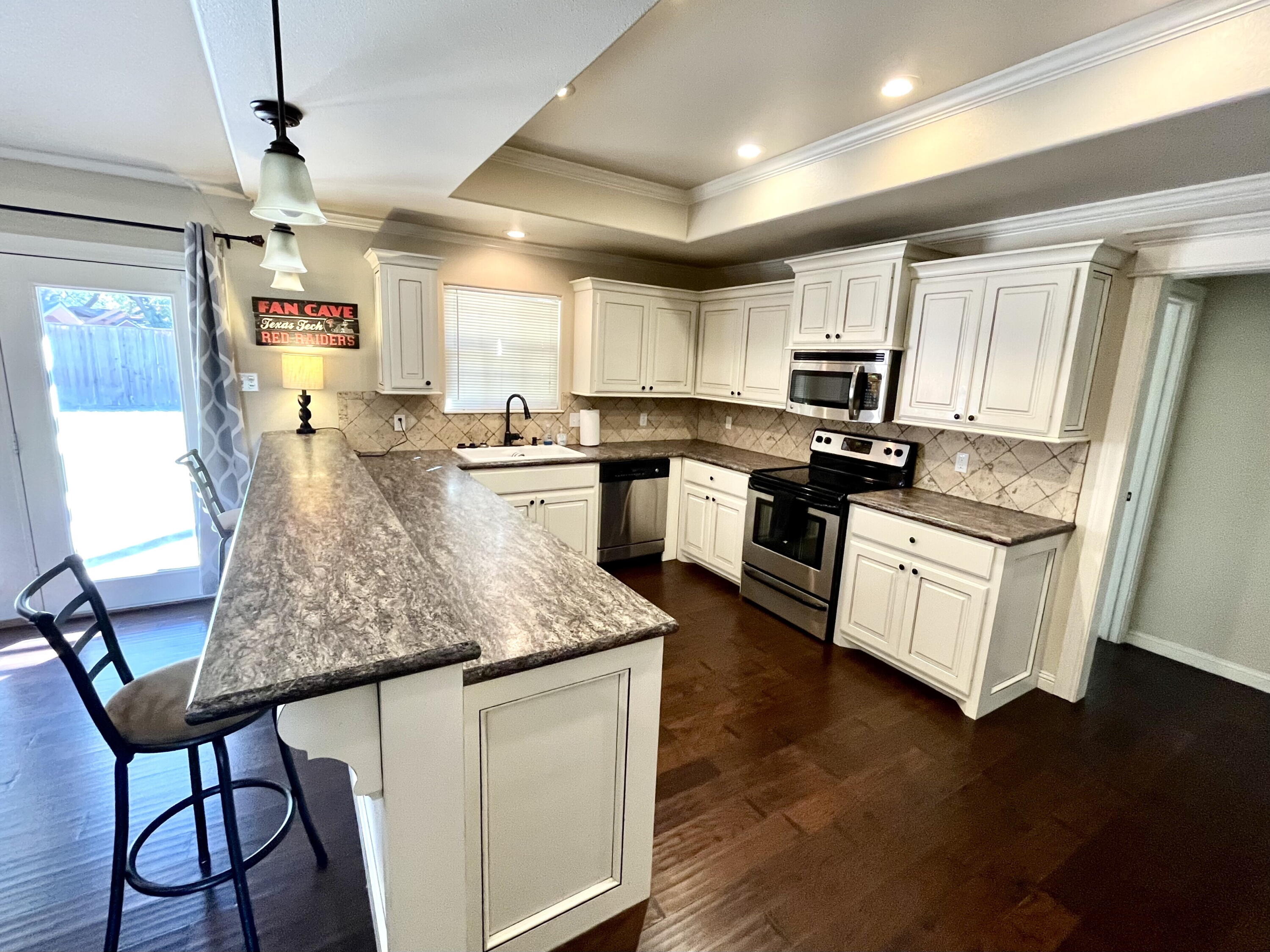 3321 55th Street Lubbock, TX 79413 - Photo 5 of 26 a kitchen with appliances cabinets and wooden floor