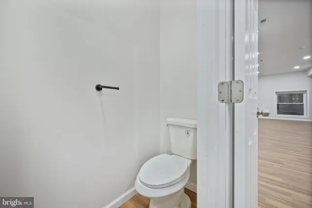 a view of kitchen and empty room with wooden floor