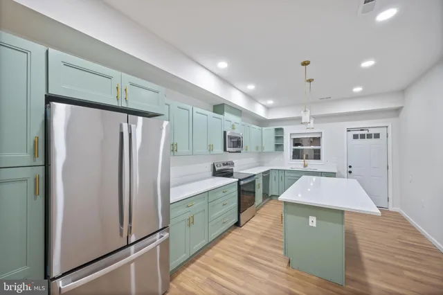 a kitchen with kitchen island a counter top space a sink stainless steel appliances and cabinets