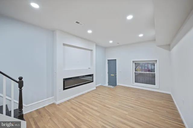 a view of an empty room with a kitchen and a window