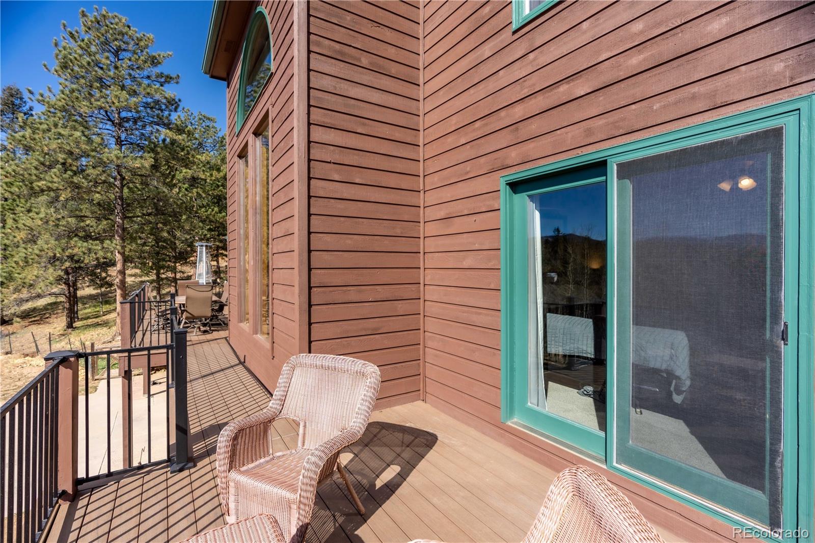 318 Rd D Pine, CO 80470 - Photo 15 of 50 a view of a patio with table and chairs and couches with wooden floor and fence and a yard