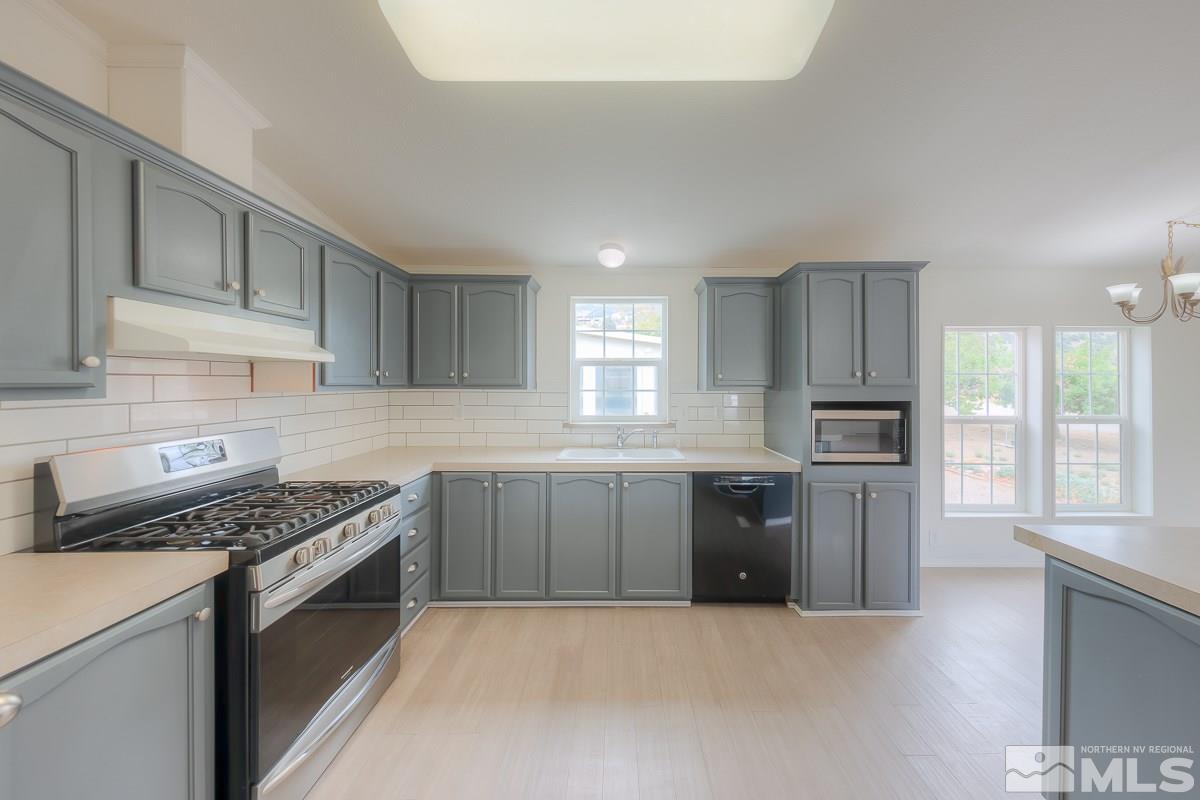 15186 Pinion Drive Reno, NV 89521 - Photo 11 of 20 a kitchen with stainless steel appliances granite countertop a stove a sink dishwasher a refrigerator and white cabinets with wooden floor