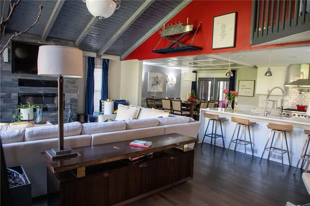 a large living room with stainless steel appliances kitchen island granite countertop a table chairs and a large window