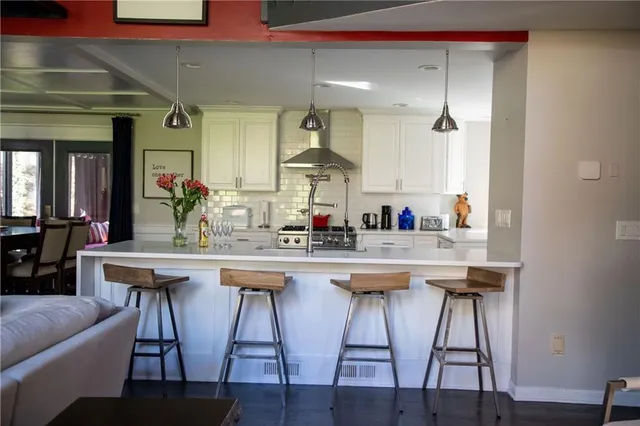 a kitchen with stainless steel appliances granite countertop a white cabinets and chairs