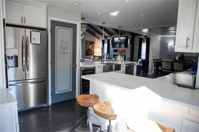 a kitchen with stainless steel appliances kitchen island granite countertop a refrigerator a stove a sink a dining table and chairs with wooden floor