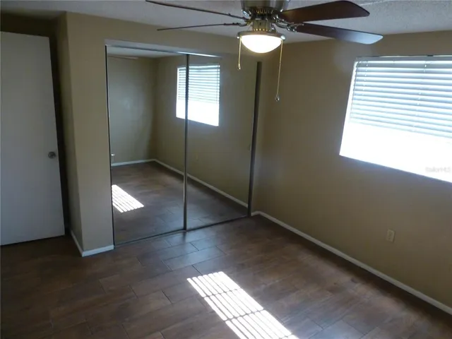 a view of an empty room with window and wooden floor